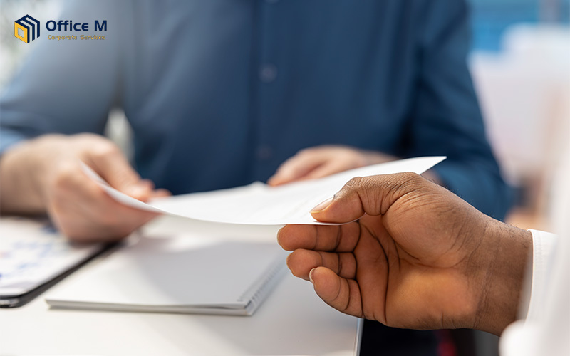 Hand passing a document across a desk during a business exchange.