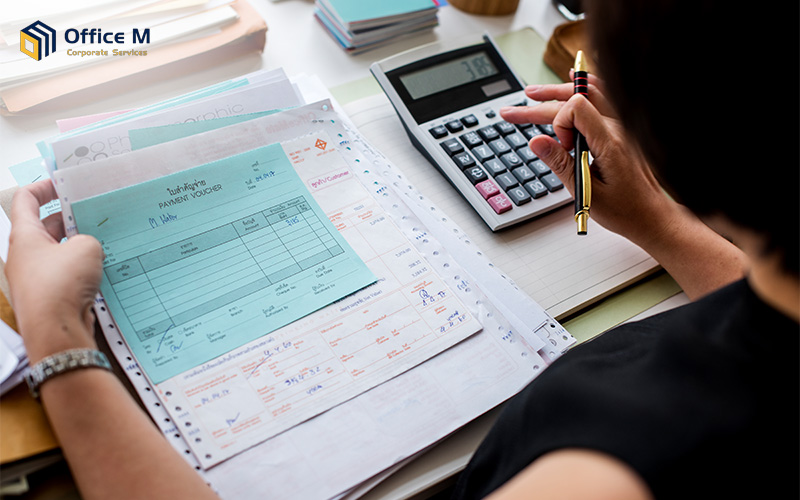 Accountant calculating tax payments on a calculator with receipts.