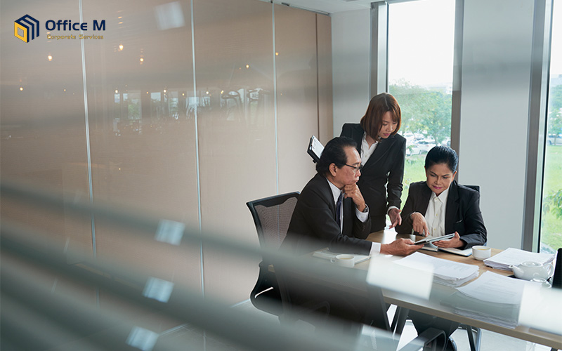 Business executives at a small company in Singapore reviewing financial reports and documents during a private consultation in the office.