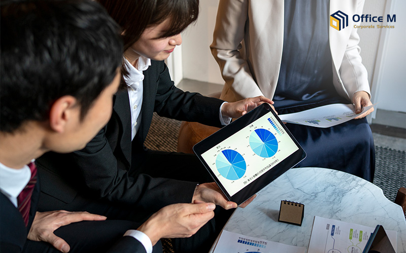 Office M consultants discussing revenue reports with clients.