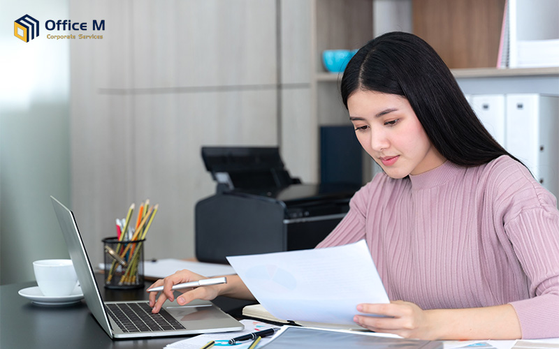 Singapore SME owner checking tax documents on laptop.