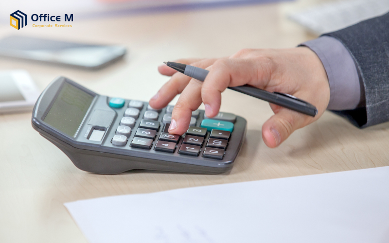 A person using a calculator and a pen for tax calculation