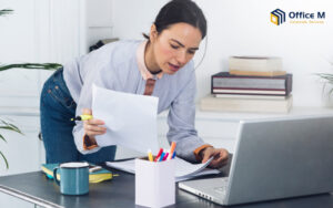 A woman reviewing tax documents and a laptop for IRAS filing.