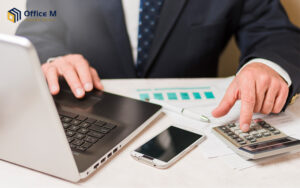 Business owner filing tax-deductible expenses using a calculator.