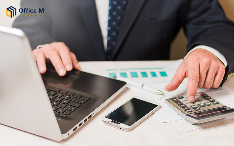 Business owner filing tax-deductible expenses using a calculator.